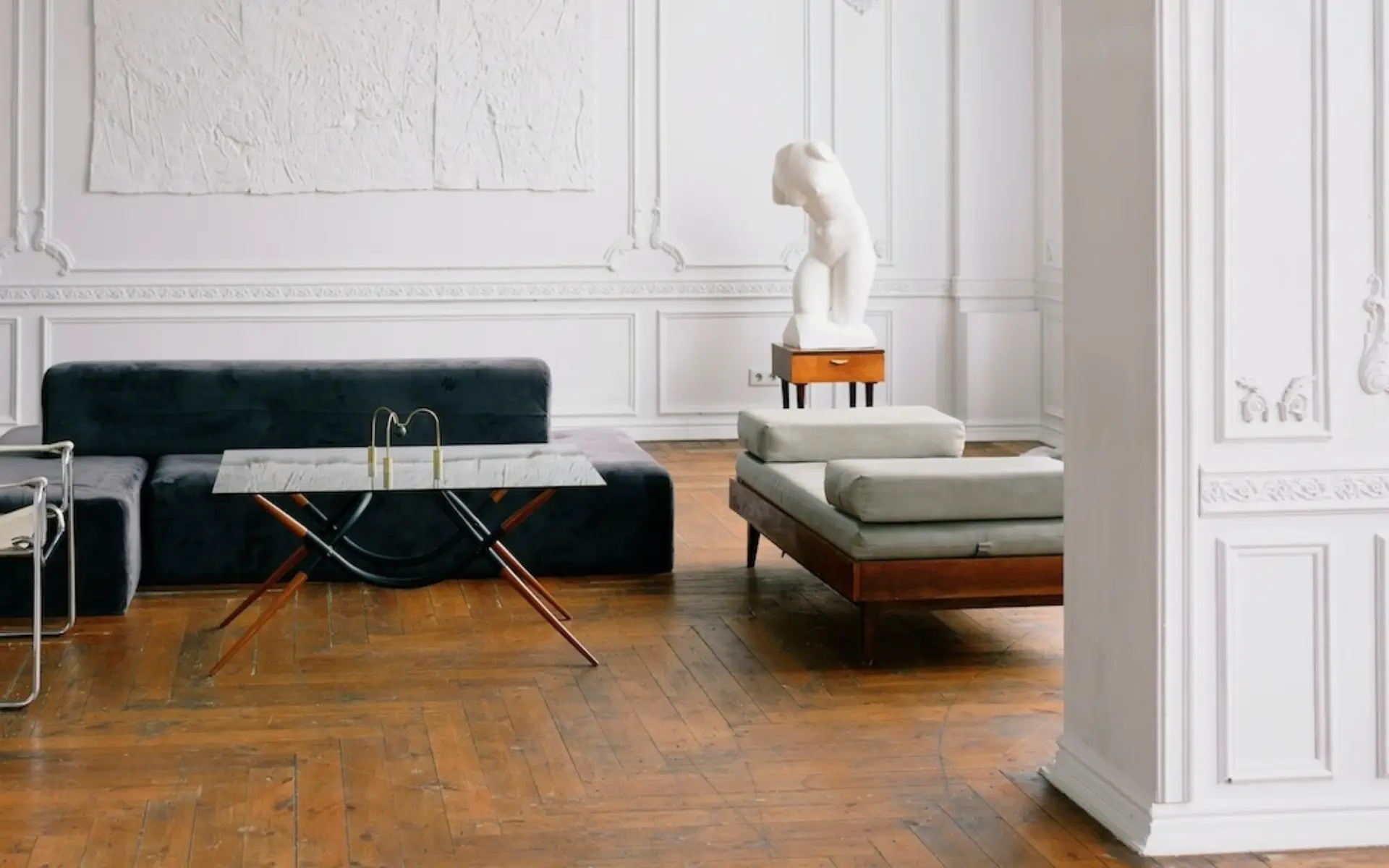 Elegant living room with white panelled walls, a dark green sofa, a glass coffee table and a chaise longue