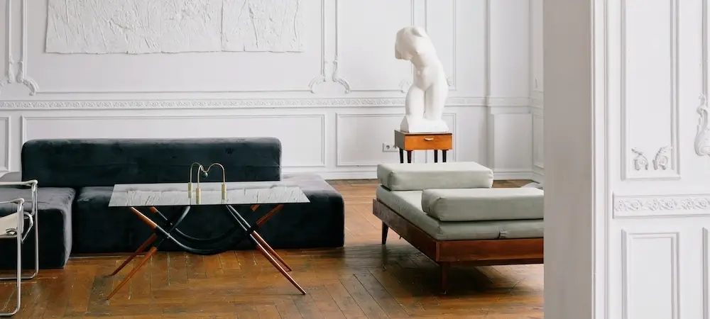 Elegant living room with white panelled walls, a dark green sofa, a glass coffee table and a chaise longue